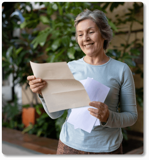 mature hearing aid patient looking at a letter from Hear For You RI